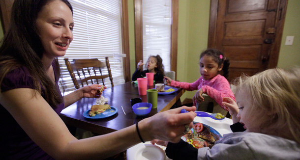 A mother serves lunch to her three children. She is a single mother and full-time student, and food stamps often don't cover the food her family needs each month. (AP/M. Spencer Green)