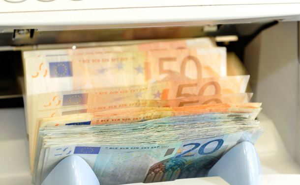 A machine counts euro bank notes at a bank in Dresden, Germany. As the euro falls in value it increases the competitiveness of European exports relative to ours. (AP/Matthias Rietschel)