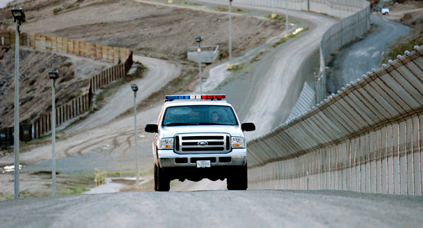 A United States Border Patrol vehicle cruises between the long primary and secondary fence line in San Diego. (AP/Lenny Ignelzl)