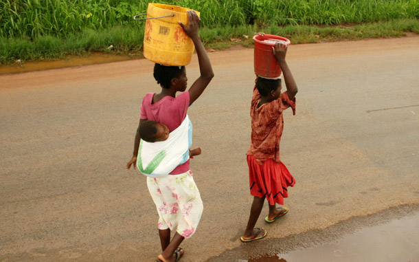 Children, one with a child on her back, carry collected water in containers on their heads in Harare, Zimbabwe. The G8 summit this weekend offers President Obama the opportunity to push for a broad human rights agenda for women that includes access to reproductive health services. (AP)