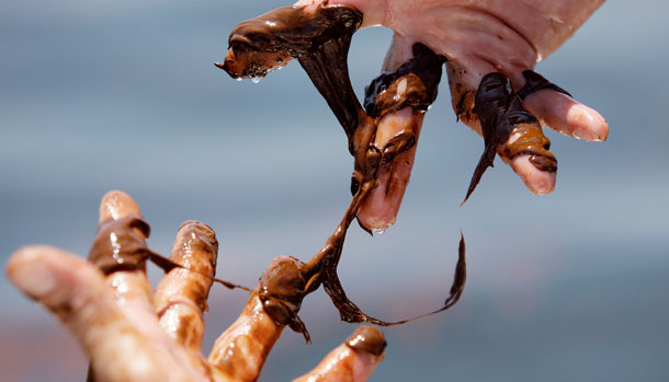 Man works to remove oil from the Deepwater Horizon spill off his hands. (AP/Eric Gay)