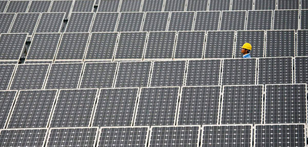 A worker walks past solar panels in a solar farm in China's Yunnan province. China is currently the world leader in clean energy technology. (AP)