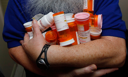 Morton Genser poses with his prescription drugs. His wife keeps track of when he'll fall into the dougnut hole and hit the Medicare Part D drug cost threshold where he has to start paying the full costs of the drugs. (AP/Wilfredo Lee)