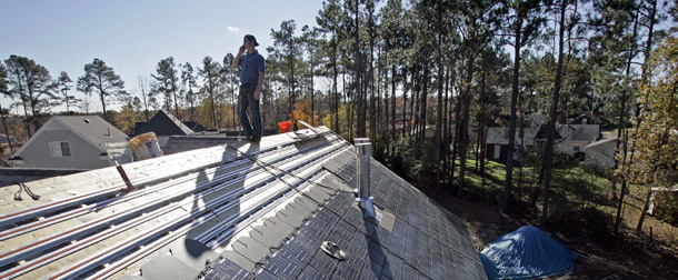 A worker installs solar-paneled roof shingles on a home in Raleigh, NC. A clean energy and climate bill should include provisions that incentivize renewable energy production and manufacturing, and more energy efficient homes. (AP/Gerry Broome)