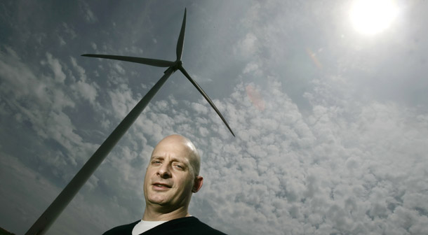 Project developer Stephan Noe is dwarfed by one of the 400-foot-high wind turbines at the Crescent Ridge Windpower Project near Tiskilwa, IL. Federal loan guarantees help ensure that projects like Noe's can move forward. (AP/Charles Rex Arbogast)