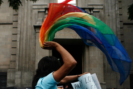 Una mujer con una bandera de arco iris durante una manifestación afuera de la Suprema Corte en la Ciudad de México, cual votó el 16 de agosto, 2010 para confirmar una ley permitiendo las adopciones por parejas del mismo sexo en dicha cuidad. (AP/Miguel Tovar)