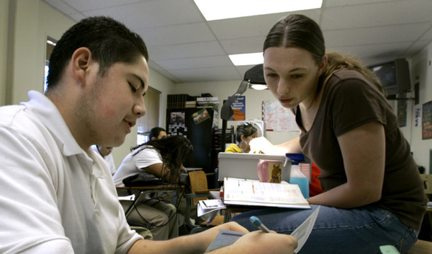 Jafet Carrasco, estudiante de primer año, resuelve un problema algebraico con su maestra Jennifer Morelock en Alta Vista Charter School en Kansas City, MO. Los estudiantes que viven en áreas metropolitanas que comparten múltiples limites estatales enfrentan dificultades particulares al completar sus títulos universitarios. (AP/Charlie Riedel)