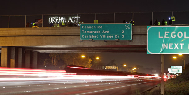 Rush hour traffic races past an underpass where students hold a candle light vigil in support of the Dream Act on November 29, 2010, in Carlsbad, CA. (AP/Lenny Ignelzi)