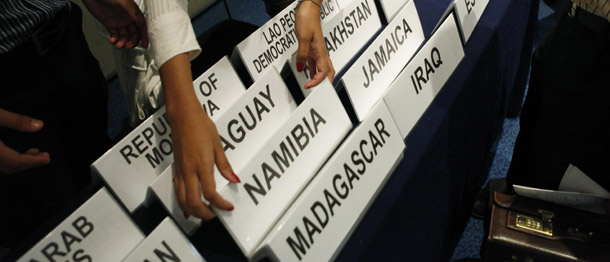 A woman hands out names of countries to participants at the United Nations Climate Change Conference in Cancun, Mexico, on December 2, 2010. Japan announced at one of the opening plenary sessions of the talks that they would not renew their emission reduction pledges under the Kyoto Protocol once the first round of required carbon cuts expire in 2012. (AP/Eduardo Verdugo)