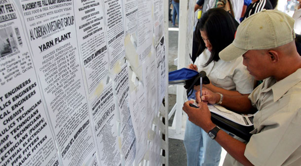 Workers take notes from a lob-listing board in the Phillipines. (AP/Pat Roque)