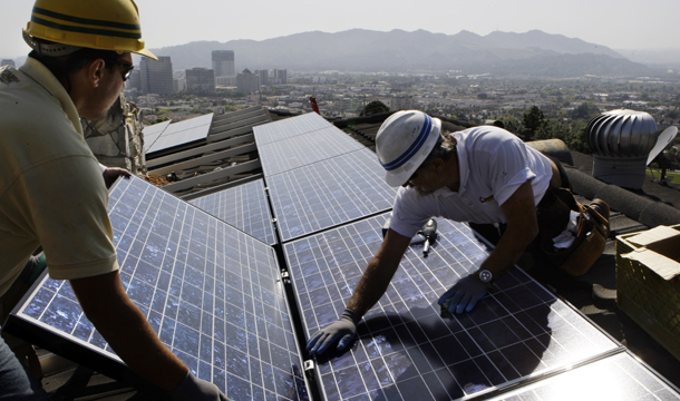Team leader Edward Boghosian, right, and electrician Patrick Aziz, both employees of California Green Design, install solar electrical panels on the roof of a home in Glendale, CA. (AP/Reed Saxon)