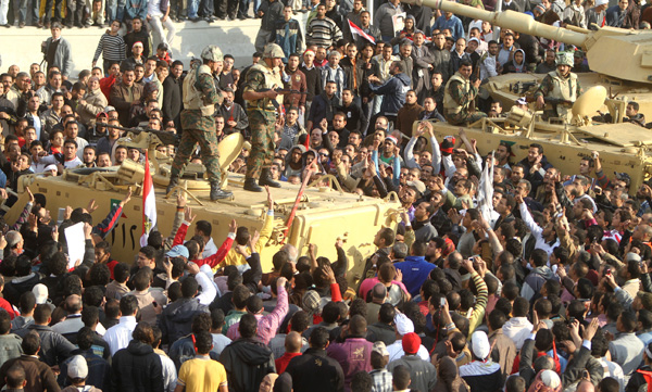 Armed soldiers look down on protesters surrounding military vehicles in Tahrir Square in Cairo, Egypt, February 2, 2011. (AP/Ahmed Ali)