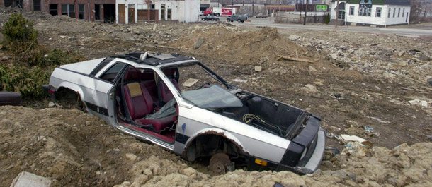 An abandoned car sits next to an abandoned building across the river from downtown Youngstown, Ohio. Youngstown and the surrounding Mahoning County in northeastern Ohio are rapidly undergoing a population decrease. (AP/Mark Duncan)