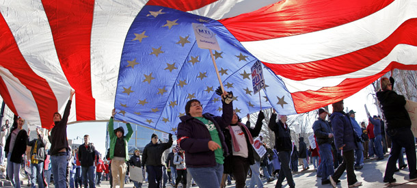 Pro-union protesters hold up an American flag as they march around the the State Square in Madison, Wisconsin on February 19, 2011. (AP/Andy Manis)