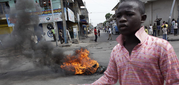 A boy gestures in front of a protest fire set by local youth shortly before security forces loyal to Laurent Gbagbo opened fire on civilians in the Treichville neighborhood of Abidjan, Ivory Coast, on March 8, 2011. (AP/Rebecca Blackwell)