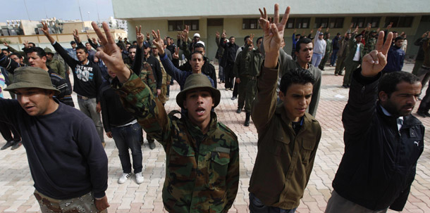New Libyan rebel recruits flash the victory sign and chant slogans as they stand in formation during a training session after signing up with the forces against Libyan leader Moammar Qaddafi at a training base in Benghazi, eastern Libya, on March 3, 2011. (AP/Hussein Malla)
