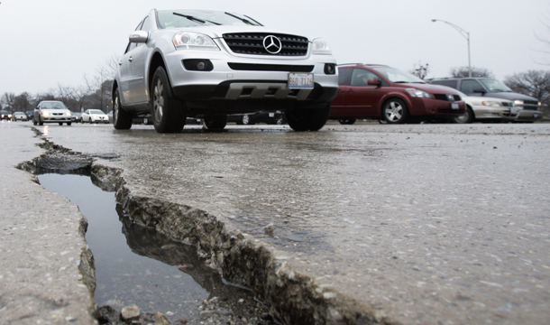 Cars pass a pothole on Lake Shore Drive in Chicago, Thursday, April 10, 2008. If passed, H.R. 1 would slash funding for all manner of  transportation projects. That means fewer highway miles repaved, fewer  new roads and bridges, and less frequent bus and train service. (AP/Charles Rex Arbogast)