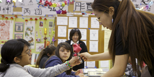 Cedarlane Middle School teacher Angela Wang, right, teaches origami in the Hacienda Heights area of Los Angeles. Despite similar student bodies and financial inputs, Los Angeles’ students score consistently lower than San Diego’s students on state reading and math exams from elementary all the way through high school. (AP/Damian Dovarganes)