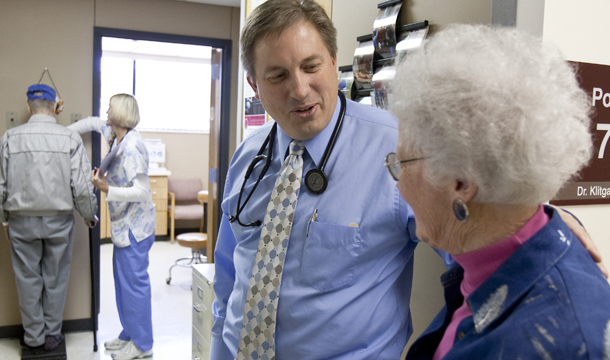 Primary care physician Dr. Don Klitgaard greets Muriel Bacon as her husband weighs in with a nurse at the Myrtue Medical Center in Harlan, Iowa. Patient-centered medical homes, like Myrtue, act as hubs for coordinating patient care among multiple providers and provide comprehensive and accessible care to their patients. (AP/Nati Harnik)