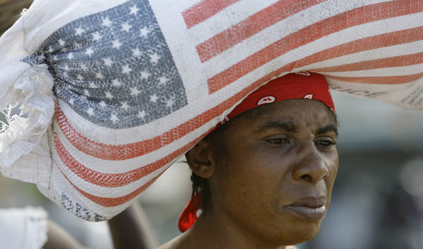 A woman carries a bag containing rice donated by USAID, as she walks through a market in Leogane, Haiti. (AP/Lynne Sladky)