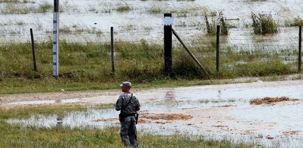 A member of the Louisiana National Guard stands guard as water diverted from the Mississippi River through a bay in the Morganza Spillway begins to fill a pasture in Morganza, Louisiana. (AP/Patrick Semansky)