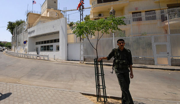 A Syrian security man stands guard in front of the U.S. embassy in Damascus, Syria, a day after pro-government protesters smashed windows and sprayed obscenities and graffiti on the walls of the embassy to protest the visit last week by the American and French ambassadors to Hama, an opposition stronghold in central Syria. (AP/Muzaffar Salman)