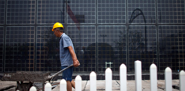 A worker transports a cart of  cements in front of a building covered in a wall of solar panels at a  factory of Yingli Green Energy Holding Co. in Baoding, in northern  China's Hebei province, June 20, 2011. (AP/Alexander F. Yuan)
