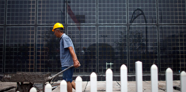 A worker transports a cart of cements in front of a building covered in a wall of solar panels at a factory of Yingli Green Energy Holding Co. in Baoding, in northern China's Hebei province, June 20, 2011. (AP/Alexander F. Yuan)