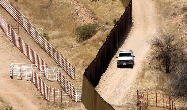 A U.S. Border Patrol vehicle rides along the border fence separating Nogales, Arizona, right, from Nogales, Mexico. (AP/Gregory Bull)