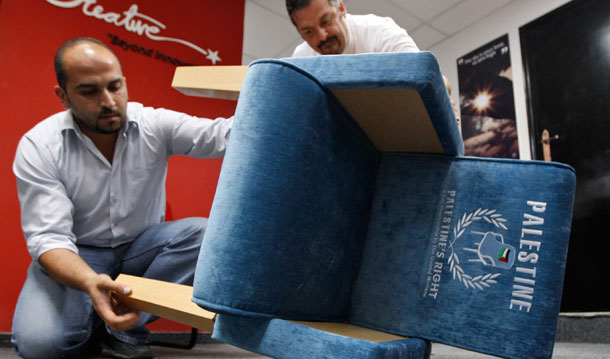 Palestinians assemble the legs of a chair covered with embroidered blue upholstery featuring a Palestinian flag and the word "Palestine." (AP/Majdi Mohammed)