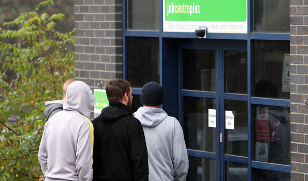 People are seen queuing outside a Jobcentre Plus at Gateshead, England, Wednesday, October 12, 2011. In the United Kingdom the government’s “Work Programme” outsources job brokerage and employability support to a small number of providers. Providers are paid largely for outcomes, not activity. In this case the outcome is finding a participant sustained employment for 26 weeks or more. (AP/Scott Heppell)