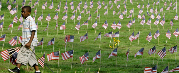 A child places flags for veterans at Highland Park Cemetary in Highland Hills, Ohio. Our service members and veterans continue to face challenges before, during, and after deployments, from combat stress injuries to unemployment. (AP/Tony Dejak)