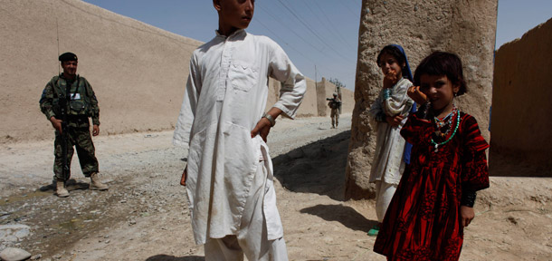 Afghan children stand near U.S. Marines and Afghan soldiers jointly patrolling in Helmand province, southern Afghanistan, September 5, 2011. (AP/Brennan Linsley)