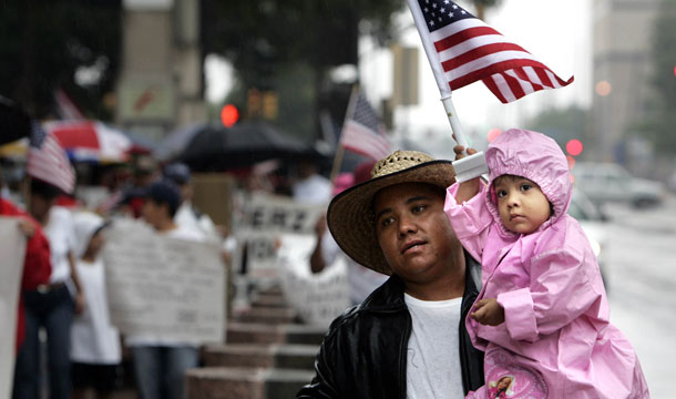 Salome Gomez, left, carries his 2-year-old daughter, Adriana Gomez, in light rain during an immigrant rights march in downtown Dallas, Texas. The vast majority of Americans support smart solutions to immigration reform and reject mass deportation. (AP/LM Otero)