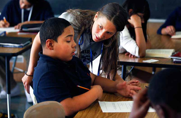 A teacher helps a student with schoolwork. Wraparound services allow for fewer health realted issues that cost students instructional time, among other benefits. (AP/Alex Brandon)