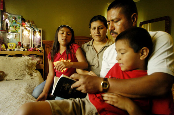 Jose Aguilar, y su esposa, Maria, leen un libro con sus hijos, Jose Jr., 7, y Jennifer, 9, en su casa en National City, California. Algunos conservadores en el Congreso quieren pagar por el recorte de impuestos salariales del 2012 con un aumento a los impuestos de algunas familias inmigrantes . (AP/Sandy Huffaker)