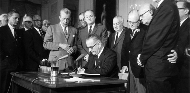 El presidente Lyndon Johnson firma el Acta de Derechos Civiles (CRA por sus siglas en ingles) en el Salón Este de la Casa Blanca en Washington, el 2 de julio, 1964. El CRA, junto con la Ley de Seguro Social y la Ley de Educación Superior, fueron leyes claves para la clase media. (AP)