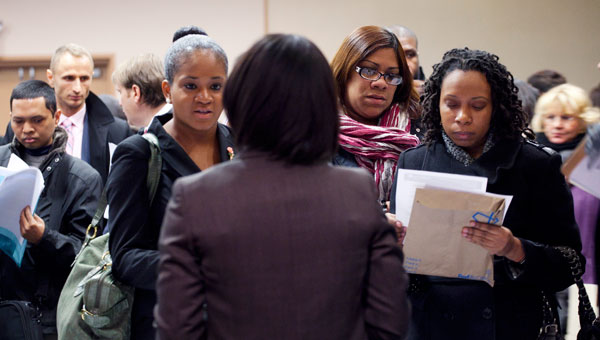 People talk with a recruiter, center, at a December 2011 job fair sponsored by National Career Fairs, in New York. (AP/Mark Lennihan)
