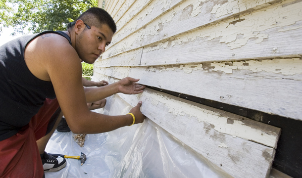 Edwin Aguilar replaces siding during weatherization work on a home in Grafton, Nebraska. (AP/Nati Harnik)