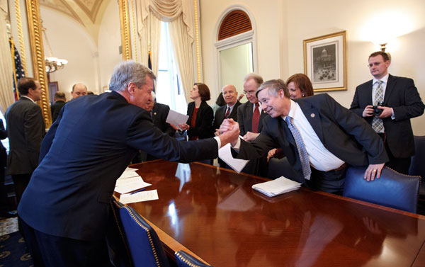Senate Finance Committee Chairman Sen. Max Baucus (D-MT), left, reaches out to Rep. Fred Upton (R-MI) to celebrate as members of the bipartisan House and Senate conferees on the payroll tax cut extension signed the compromise agreement. (AP/J. Scott Applewhite)