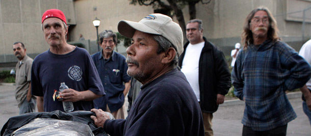Homeless people wait in line to pick up hygiene kits in Santa Ana, California. Some specific program areas that governments in the United States are  beginning to explore for Social Impact Bonds include reducing  recidivism, reducing homelessness, preventive health services, workforce  development, and helping unemployed persons re-enter the workforce. (AP/Jae C. Hong)