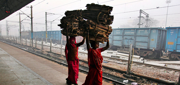 Indian women carry firewood on their heads as they arrive at a train station in Allahabad, India, on December 19, 2011. (AP/Rajesh Kumar Singh)