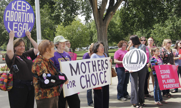 Protesters hold signs during a rally at the statehouse in Topeka, Kansas, on September 7, 2011. Religion and reproductive rights are often pitted against each other  in public debates and the media. But in real life many people of faith support reproductive rights. The Center for American Progress recently launched a new project that brings together faith leaders who advocate for these rights. (AP/Orlin Wagner)