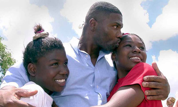 Dennis Allen, center, hugs and kisses his daughters in Tulia, Texas. Many families in communities of color have been particularly hard hit by the Great Recession and have had a harder time is the recover, as well.
<br /> (AP Photo/LM Otero)