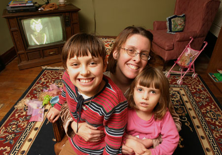 Lisa Seelye, a single mother working for minimum wage at a fast food restaurant, sits with her  daughters. Female-dominated industries, like food service, are the least likely to offer paid sick days, in spite of the fact that women are the most likely to need to miss work to care for a sick child, partner, or parent. (AP/ Ross Weitzner)