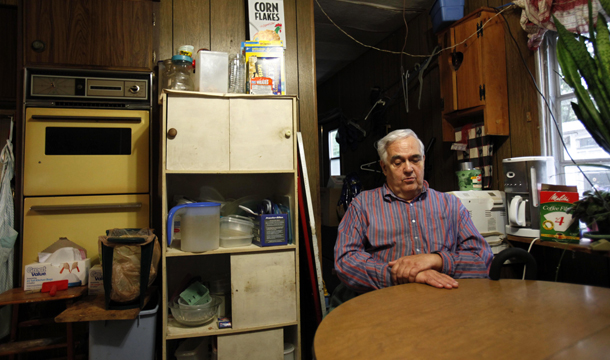 In this September 15, 2011, photo, Bill Ricker, 74, sits at the kitchen table of his trailer home in Hartford, Maine. Ricker, who has two college degrees, was injured in the late 1980s and hasn't worked since. Now he receives supplemental nutrition assistance and heating fuel assistance and gets donations from a local food pantry. (AP/Robert F. Bukaty)