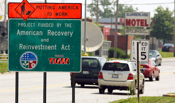 A road sign reading "Putting America to Work" and "Project Funded by the American Recovery and Reinvestment Act" is seen along Route 120 in Waukegan, Illinois. The Recovery Act, along with the Troubled Assets Relief Program, payroll tax cuts, and extended unemployment benefits, all helped boost economic recovery. (AP/Jim Prisching)