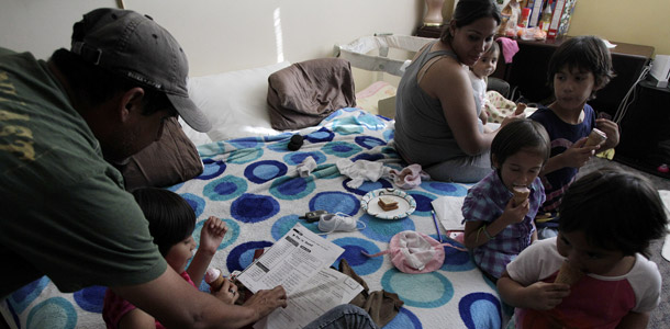 Antoine Reyes, left, helps his daughter Ashley with her homework as his four other daughters and his wife Susan eat ice cream in their family shelter at Union Rescue Mission in Los Angeles. Increasing inequality is hurting our economic growth.
<br /> (AP/Jae C. Hong)