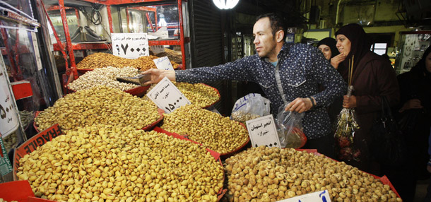 An Iranian vendor sells pistachio in Tehran's old main bazaar. Some economists estimate that international sanctions have pushed annual inflation in Iran as high as 60 percent.  (AP/Vahid Salemi)