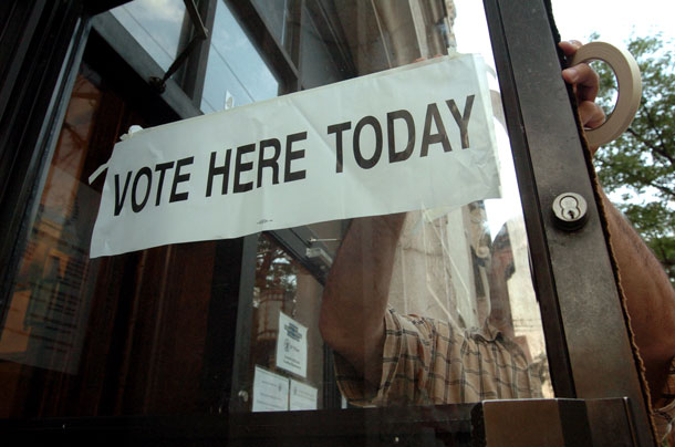 Poll worker Edwan Hosario posts a sign on the door of the Jersey City  Public Library for the New Jersey primary elections in Jersey City, New  Jersey. (AP/ Marko Georgiev)